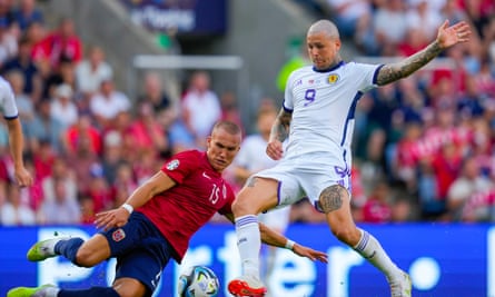 Lyndon Dykes mendapatkan bola di depan bek Norwegia yang meluncur untuk mencetak gol penyeimbang Skotlandia.