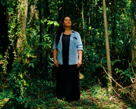woman in a forested area wearing a long black dress and a pale blue shirt