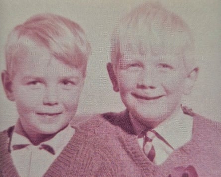 Two boys with blond hair, wearing white shirts, and V-neck jumpers. The boy on the right is wearing a tie.