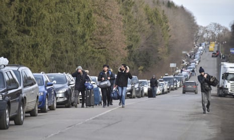 People walk past a queue of cars