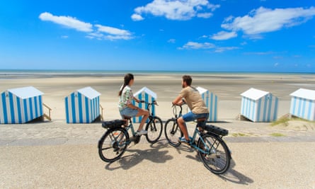 Two people cycling along the beach