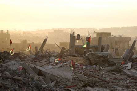 Palestinian flags flutter on top of rubble