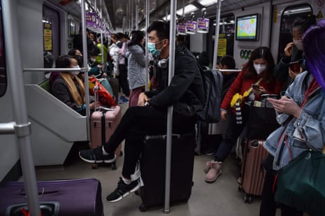 A man wearing a protective mask sits on luggage as he travels on the subway in Shanghai on January 22, 2020
