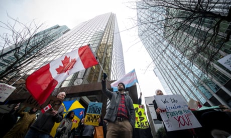 People hold signs and wave flags in a protest outside the US consulate in Vancouver