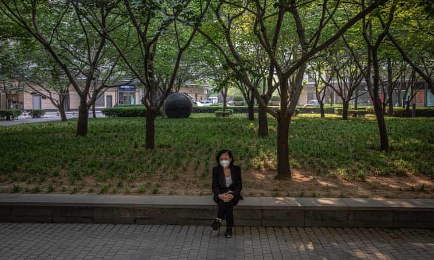 A woman sits in a square in Beijing, where lockdown measures have been eased.