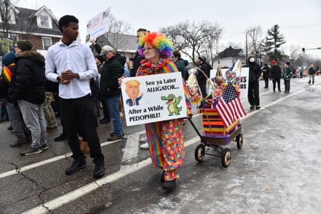 A woman dressed in clown costume holding an anti-Trump sign, rolls her wagon while clergy, faith and community leaders gather to call for ICE to leave the community following the fatal shooting of Renee Good during a law enforcement operation in Minneapolis, Minnesota, on January 8, 2026. (Photo by Octavio JONES / AFP via Getty Images)