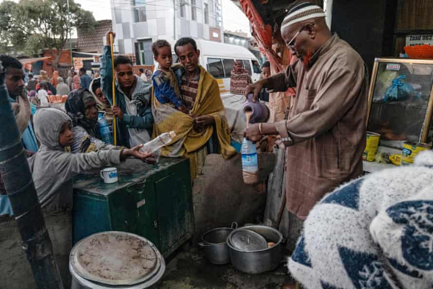 A tea shop owner offers handouts of a group of refugees