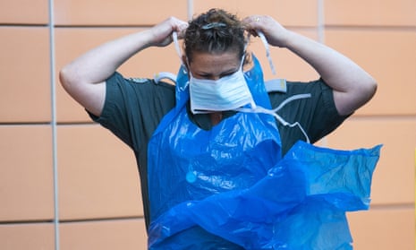 A London Ambulance worker puts on a protective mask