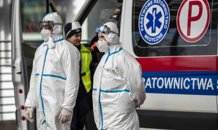 Health workers wear protective clothing as they stand to screen passengers’ temperatures at the German-Polish border.