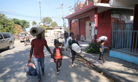 People fleeing from violence around their homes walk towards a shelter with their belongings, in Port-au-Prince, Haiti, on Saturday.
