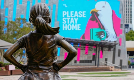 Fearless Girl statue looks at a “Please Stay Home” sign in Federation Square on the first day of a five-day COVID-19 lockdown in Melbourne