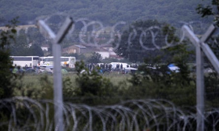 Police and buses seen through the wire fence on the perimeter of the Idomeni camp