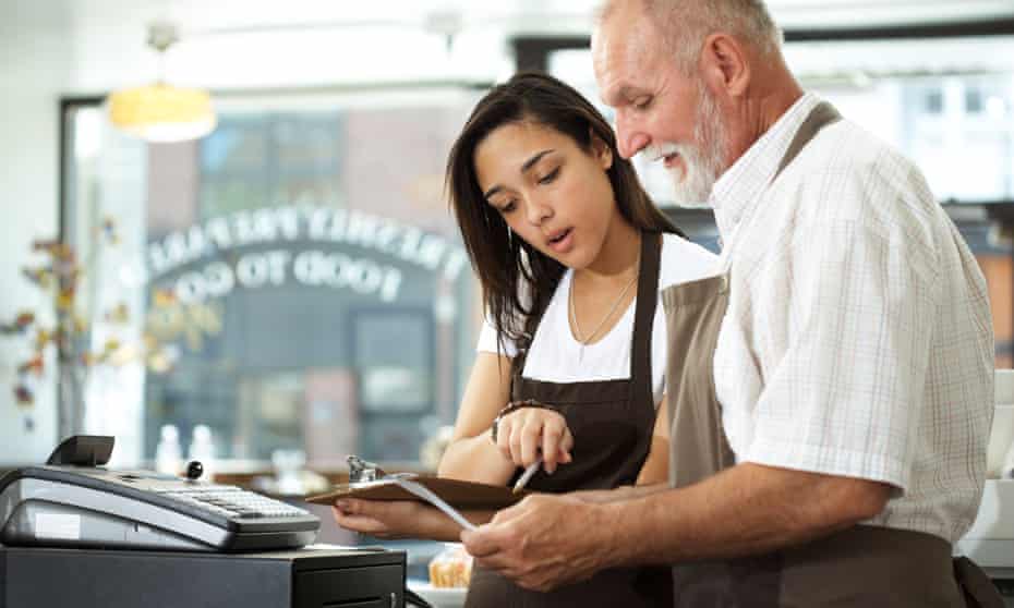A young woman and older man working in a cafe