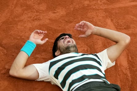 Carlos Alcaraz lies on the clay of Court Philippe-Chatrier after beating Jannik Sinner in the French Open final