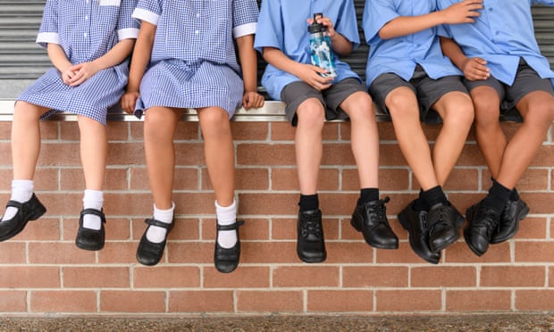 School children sitting on brick wall