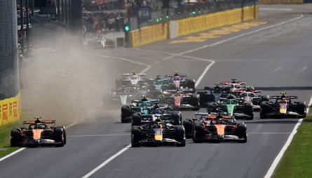 Max Verstappen leads into the first corner ahead of McLaren’s Lando Norris and Oscar Piastri with dust trailing one side of the track