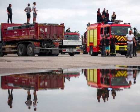 People atop a truck and a fire engine as efforts to battle wildfires continue amid drought conditions following a heatwave and water shortages across much of France, in Marcheprime, Gironde department, France.