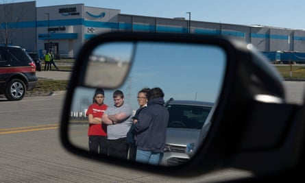 Amazon employees who knew those who died gather at the distribution center, seen in car mirror