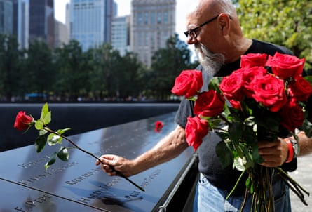 A man places a rose at a memorial
