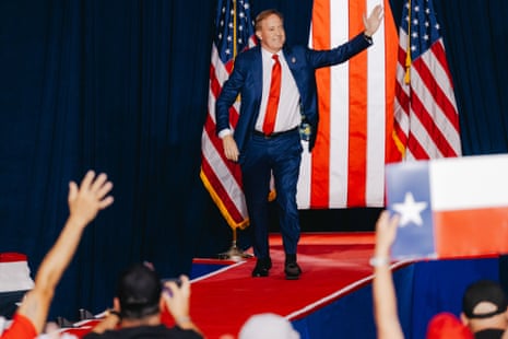 Ken Paxton waves to a crowd while walking on a red carpet