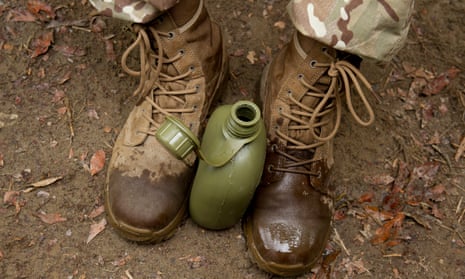 A soldier holds a water bottle between their feet