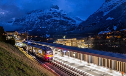 A train at the Grindelwald Terminal, with a snowy mountain in the background.