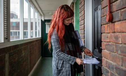 Volunteer Jessica Kleczka posts a leaflet for a local community support group called Mutual Aid through a letter box on a housing estate near the Caledonian Road in north London.