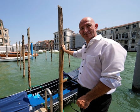 A Bezos lookalike stands in front of a Venice canal.