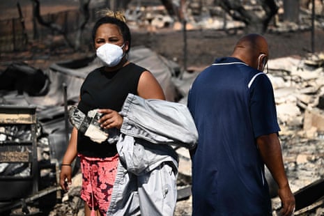 Davilynn Severson (L) holds a page of a yearbook as she and Hano Ganer (R) look for belongings through the ashes of their family’s home in the aftermath of a wildfire in Lahaina, western Maui, Hawaii on August 11, 2023.