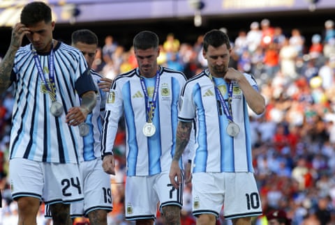 Enzo Fernández, Rodrigo De Paul and Lionel Messi wearing their silver second-place medals around their necsk