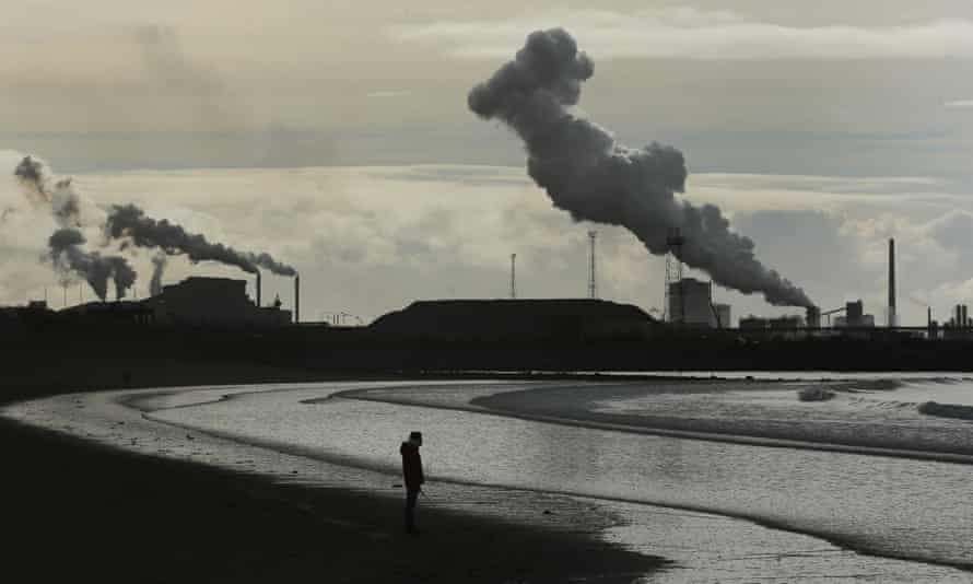 view of Port Talbot smokestacks over lonely beach