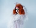Chappell Roan with voluminous orange hair and colourful makeup wears a white textured, fringed garment