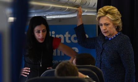Hillary Clinton talks to staff as Abedin listens onboard their campaign plane, in October 2016.