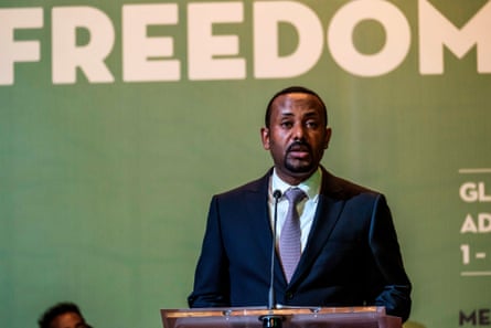 A middle-aged African man in a suit on a stage with ‘freedom’ written on the backdrop
