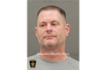 booking photo of man in grey shirt looking to side