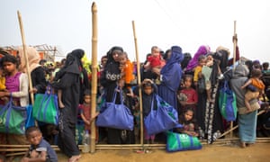 Rohingya Muslim women with their children stand in a queue outside a food distribution center at Balukhali refugee camp, Bangladesh.
