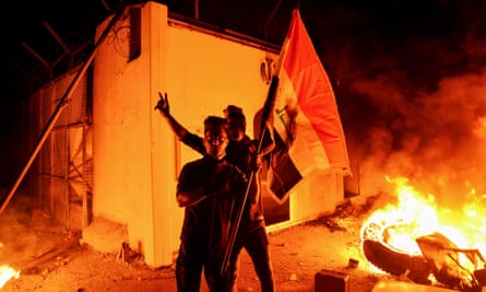 Iraqi demonstrators gesture as flames start consuming Iran’s consulate in Najaf on Wednesday.