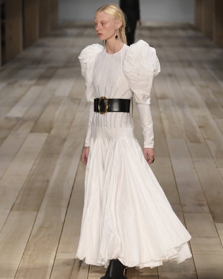 A white linen dress with puff sleeves, cinched with a wide black belt
