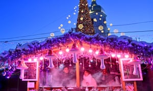 A Christmas fair in Kiev, Ukraine on Tuesday. Bright Christmas lights sit on top a stall, which is bathed in purple light as two people smile.