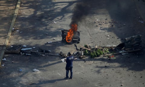 A demonstrator stands near a fire during clashes with security forces in Caracas on 1 May.