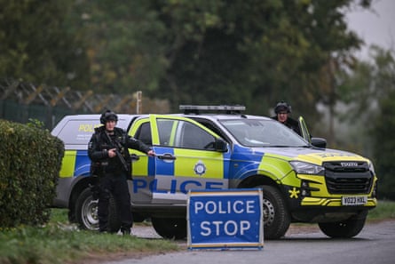 Armed police next to a police car at a roadblock