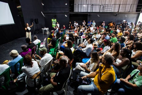 A woman on a stage addresses a seated crowd
