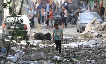 A Palestinian girls walks amidst the debris a day after an operation by the Israeli Special Forces in the Nuseirat camp in central Gaza