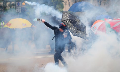 A protester throws a teargas canister back towards police in Hong Kong