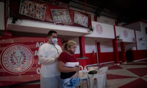 Physician Fabiano Simplicio attends a woman showing symptoms of the novel coronavirus, Covid-19, during a day of free health checks at the Unidos de Padre Miguel samba school headquarters in Rio de Janeiro, Brazil, on 24 May 2020.