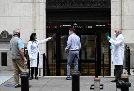Traders wearing masks arrive before the opening bell at the New York Stock Exchange (NYSE) on May 26, 2020 at Wall Street in New York City.