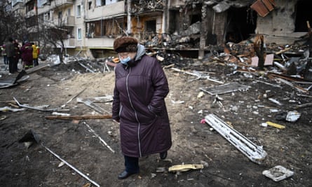 A woman walks from a damaged residential building in a suburb of Kyiv after it was reportedly hit by a shell on Friday.