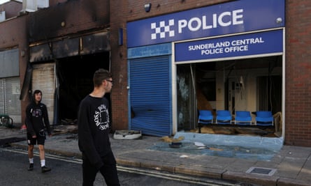 People walk past Sunderland Central Police Office after a night of violent anti-immigrant demonstrations, in Sunderland on 3 August.