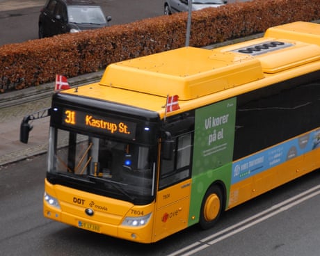 Un autobus giallo di Copenaghen con la scritta 31 per Kastrup St. e piccole bandiere danesi montate sul davanti.