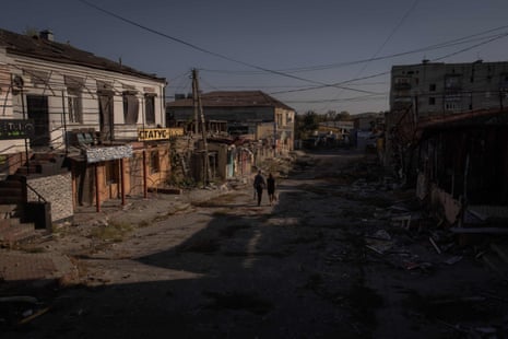 Local residents walk past damaged shops and buildings in Kupiansk, Kharkiv region.